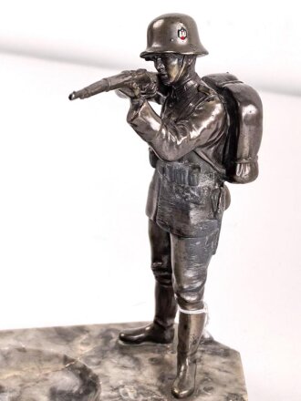 Spritzguss Figur mit Aschenbecher, einen stehenden Infanteristen mit Gewehr im Anschlag darstellend. Gesamthöhe mit Marmorsockel 17,5cm. Alte Reparaturstelle